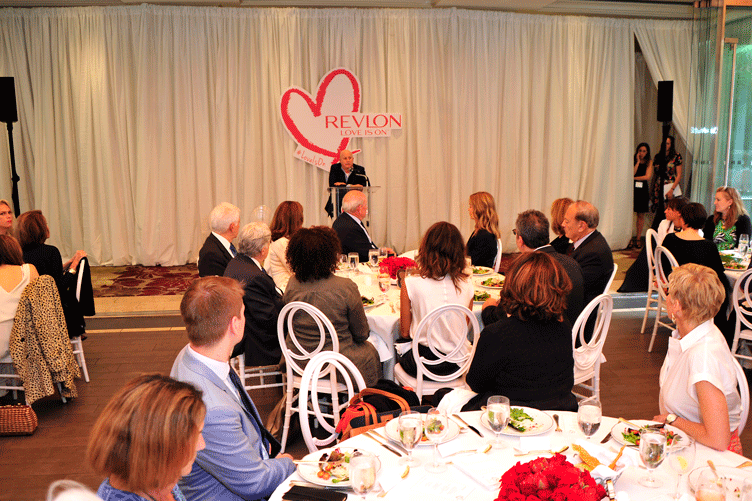 Attendees around their tables listen to a speaker at the Love is On event.