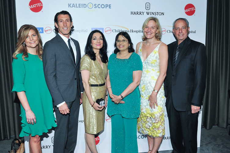 Group shot of six VIPs in front of event backdrop