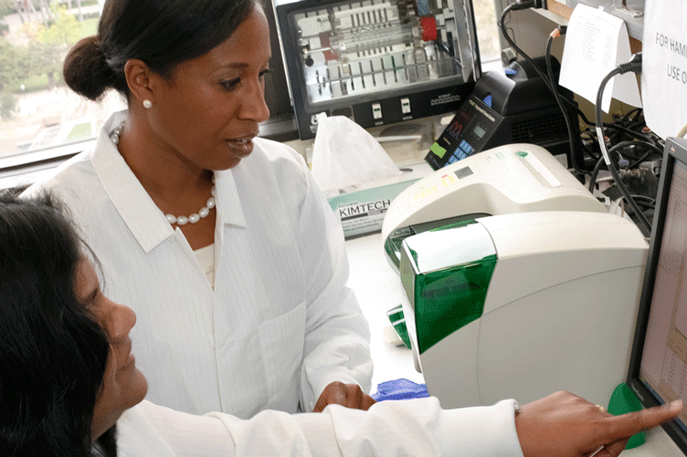 Two nurses pore over results on a computer screen.