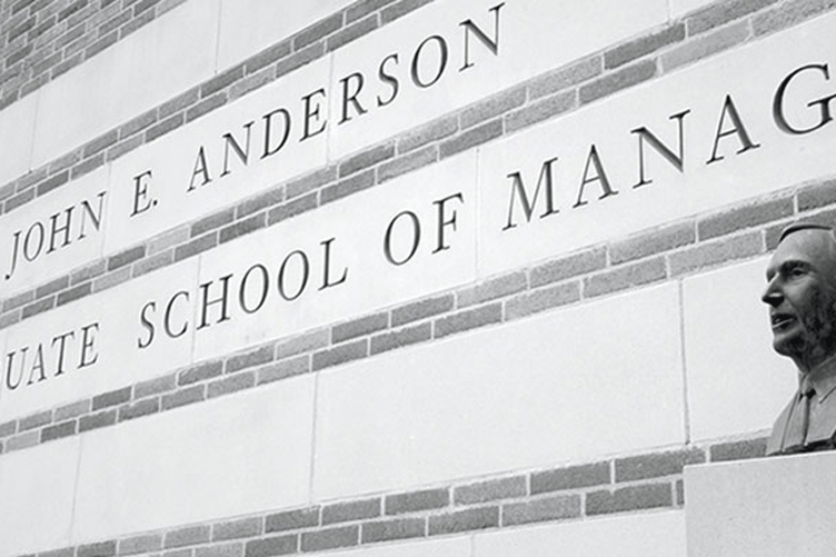 A portion of the building labeled John E. Anderson Graduate School of Management with bust in the foreground