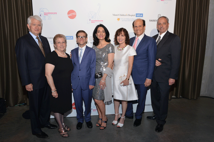 UCLA and UCLA Health leadership pose for photo with Jake Schuster in front of a backdrop with Mattel Children’s Hospital UCLA, Mattel, Kaleidoscope Ball, and Harry Winston logos on it.