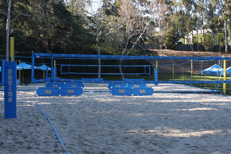 Four sand volleyball courts with UCLA and Bruins signage on nets, poles and shade umbrellas