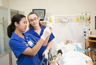 Two undergraduate nursing students in the simulation lab learn patient care using a high-fidelity manikin.
